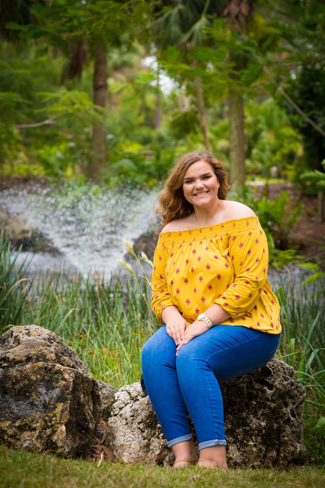 Senior portrait at Florida park with water feature and lush greenery