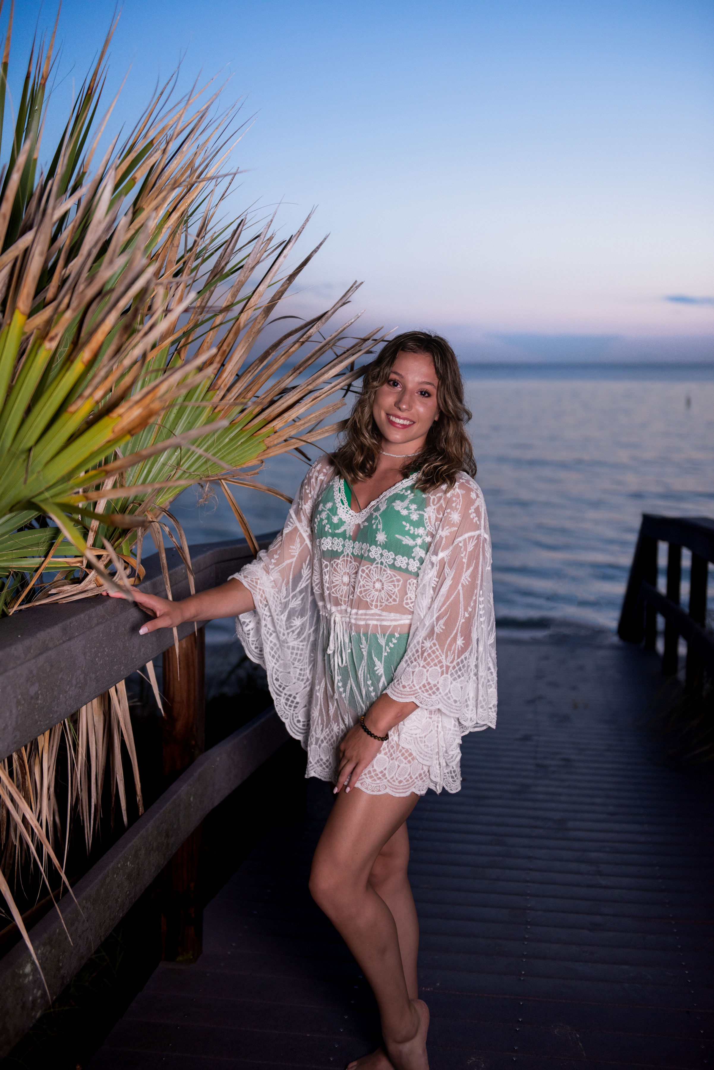 Senior portrait sitting on jetty rocks at the Gulf of Mexico at dusk